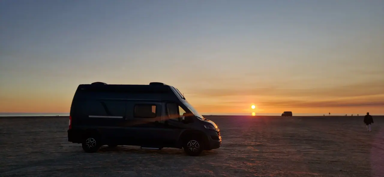 Camper als Silhouette vor dem Sonnenuntergang am Meer